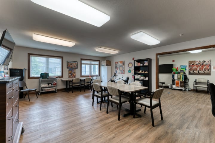 A spacious meeting room with tables, chairs, and a bookshelf.