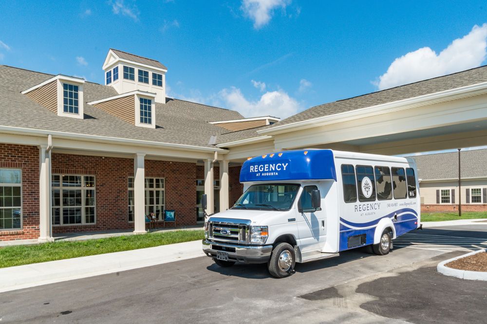 A shuttle bus parked in front of a building on a sunny day.
