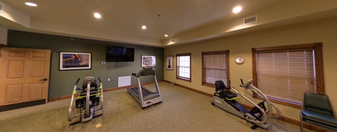 A small gym room with a treadmill and exercise machine.