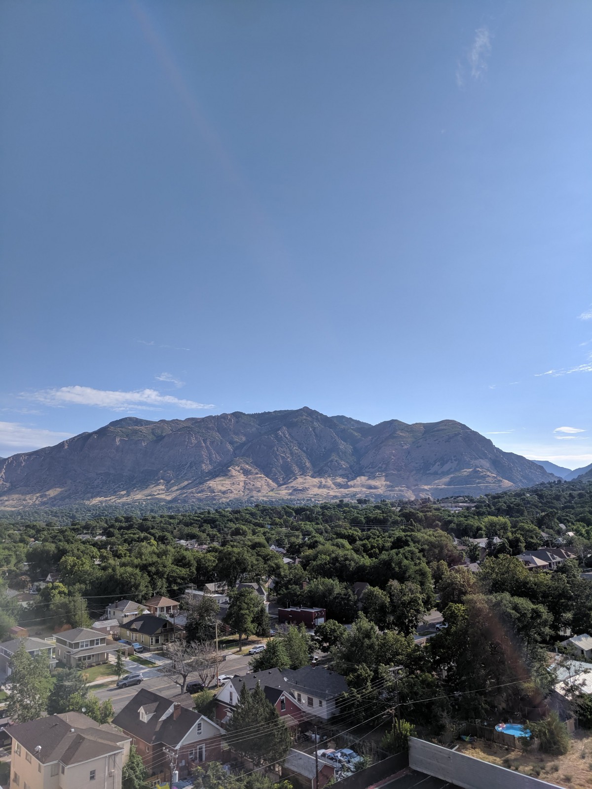 A scenic view of a mountain range with a clear blue sky and lush greenery in the foreground.