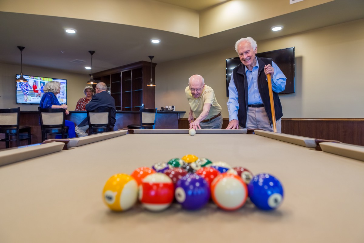 Senior citizens enjoying a game of pool in a recreation center.