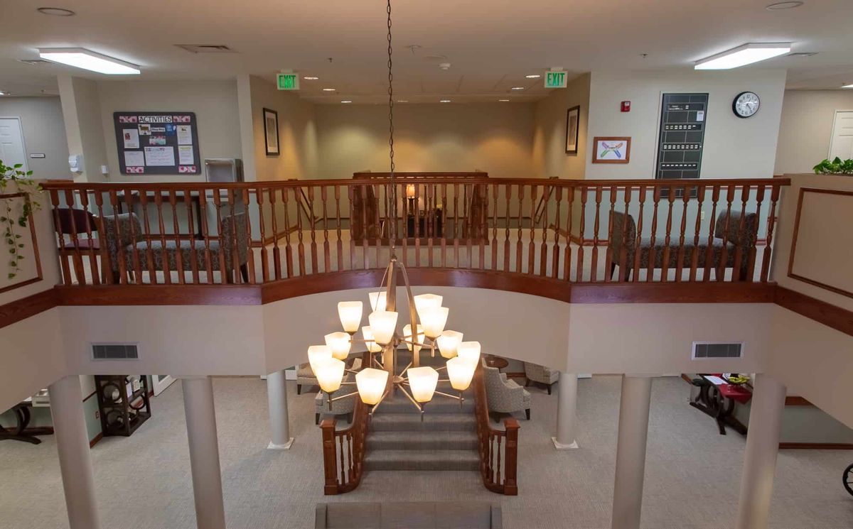 A spacious interior featuring a grand staircase with an elegant chandelier and upper balcony.