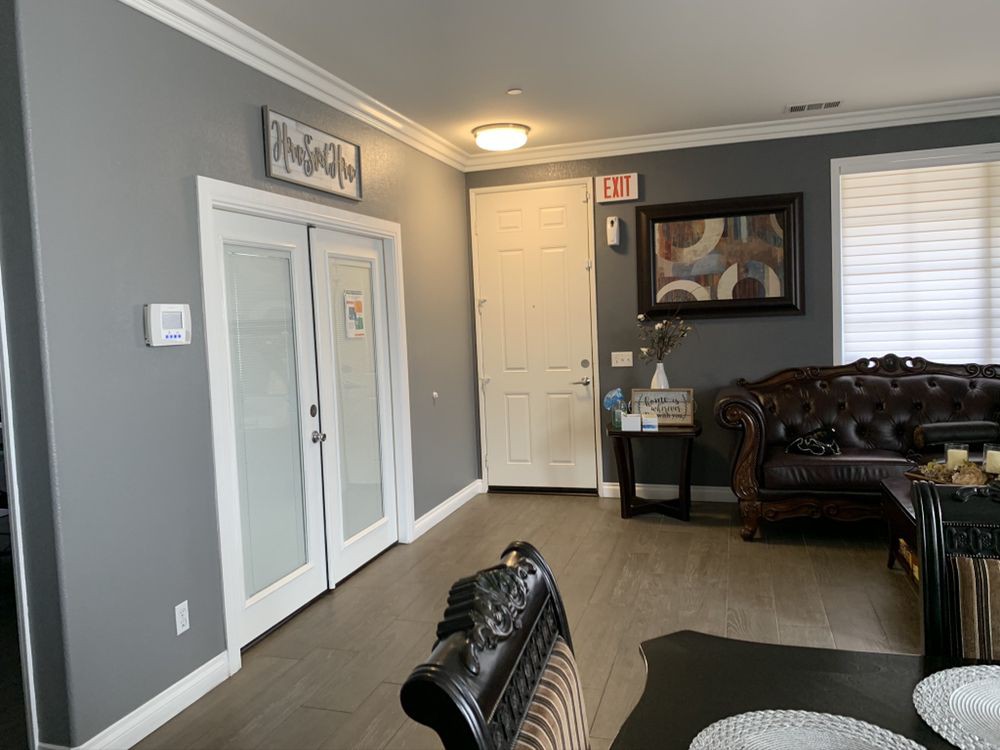 A cozy living room with elegant furniture and decor, featuring a sofa, a painting on the wall, and double doors.
