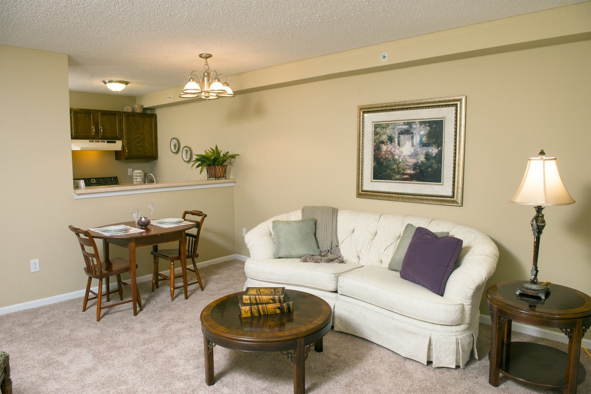 A cozy living room with a white sofa, coffee table, and an adjoining dining area.