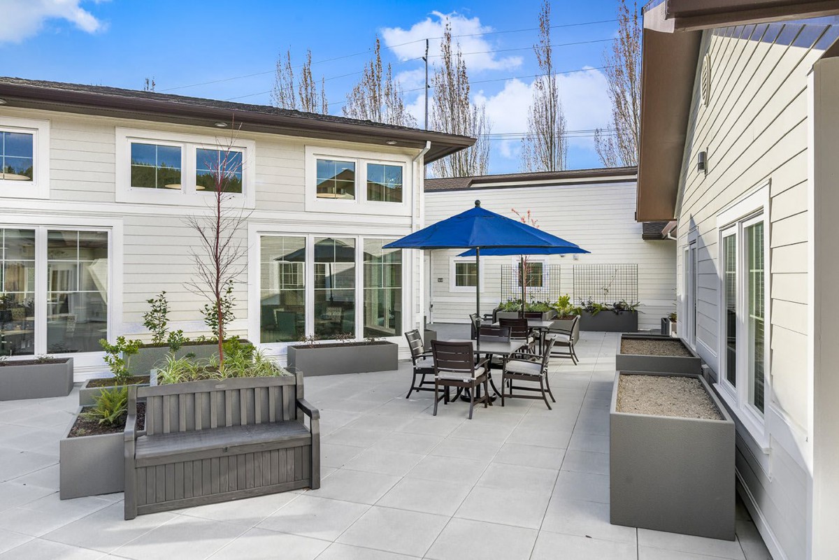 A modern patio with outdoor seating and an umbrella, set against a contemporary house exterior.