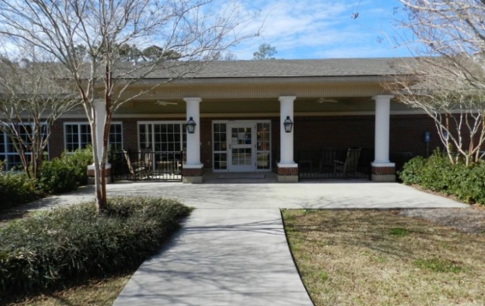 Front view of a building with a porch and columns leading to the entrance.
