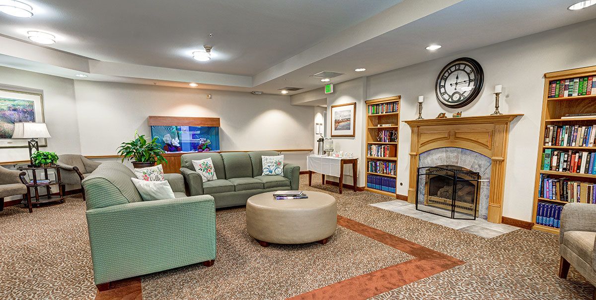 A cozy living room with a fireplace, sofas, a bookshelf, and decorative elements.