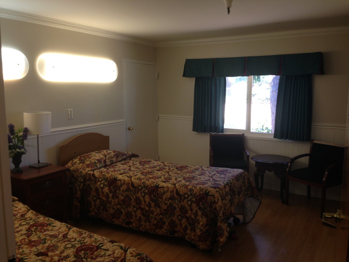 A simple hotel room with two beds and a window with curtains.