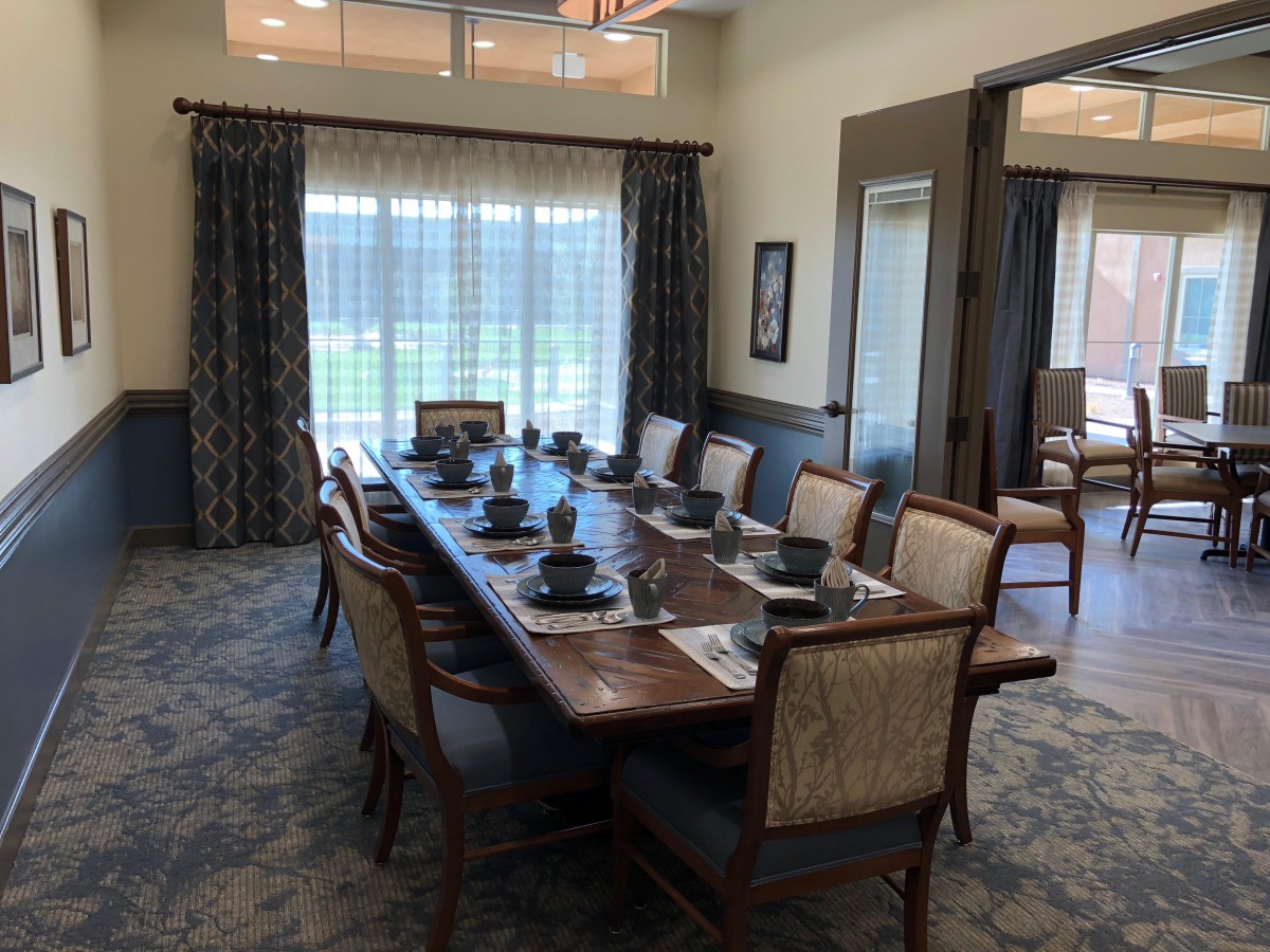 A formal dining room with a large table set for a meal, featuring elegant chairs and curtains.