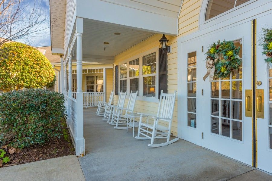 A cozy porch with white rocking chairs and a wreath on the door.