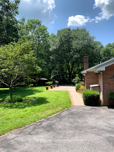 A serene outdoor scene featuring a well-maintained garden and a home, surrounded by lush greenery on a sunny day.