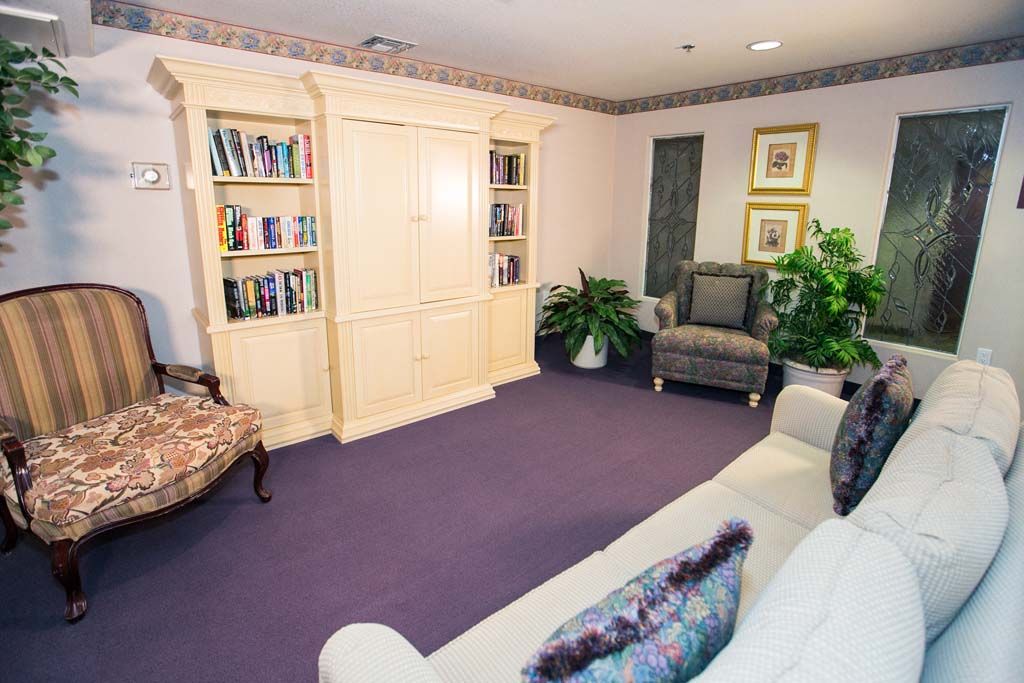 A cozy living room with bookshelves, comfortable seating, and decorative plants.