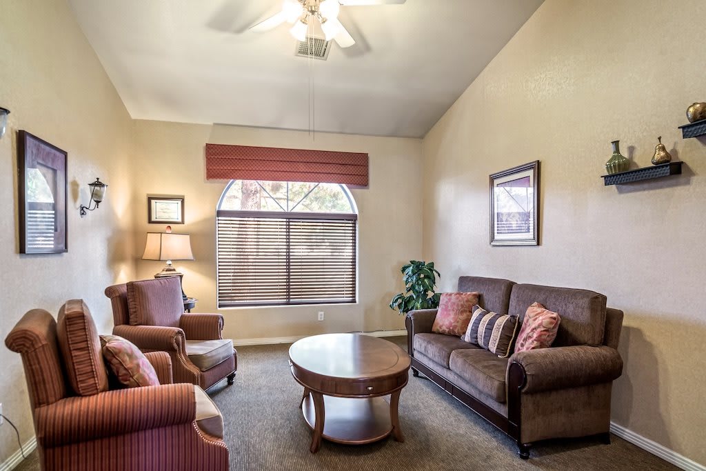 A cozy living room with a sofa, armchairs, and a coffee table near a large window.