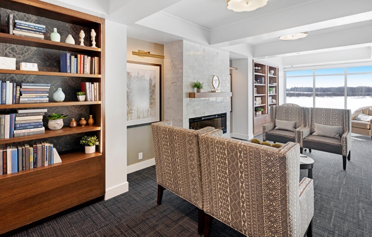 A cozy living room with bookshelves, a fireplace, and modern seating.