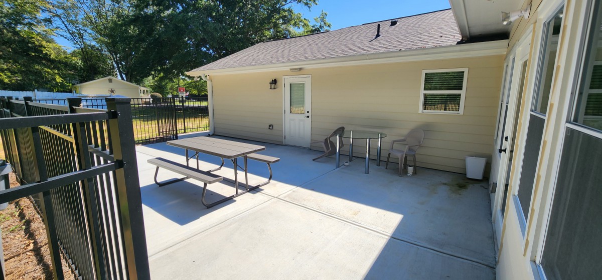 Sunny backyard patio with a picnic table and chairs.