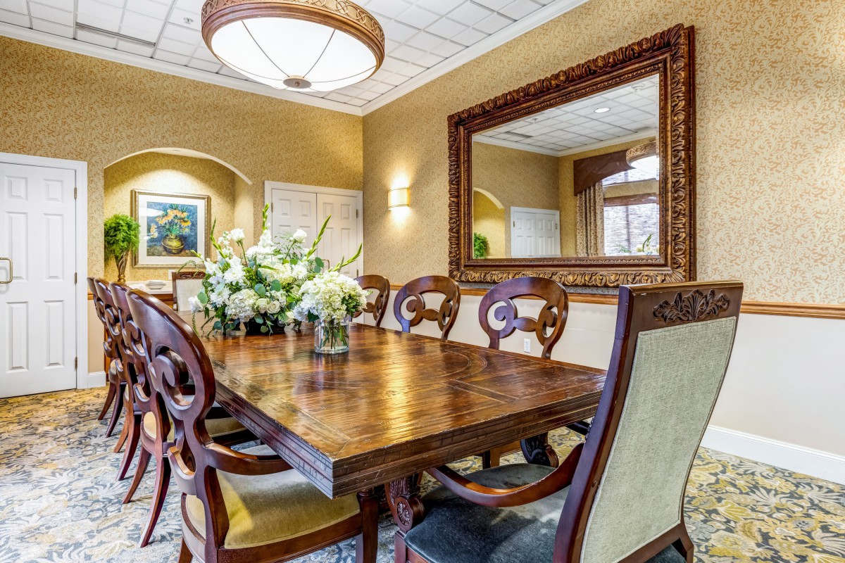 Elegant dining room with a wooden table, ornate chairs, and a decorative mirror.