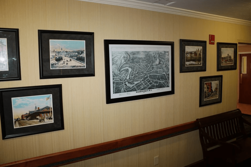 A collection of framed pictures and a map displayed on a wall in an interior setting.