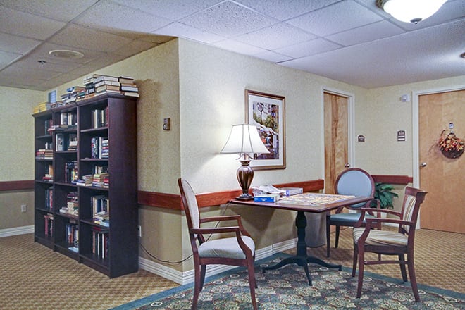 A cozy library corner with a table, chairs, and a bookshelf.