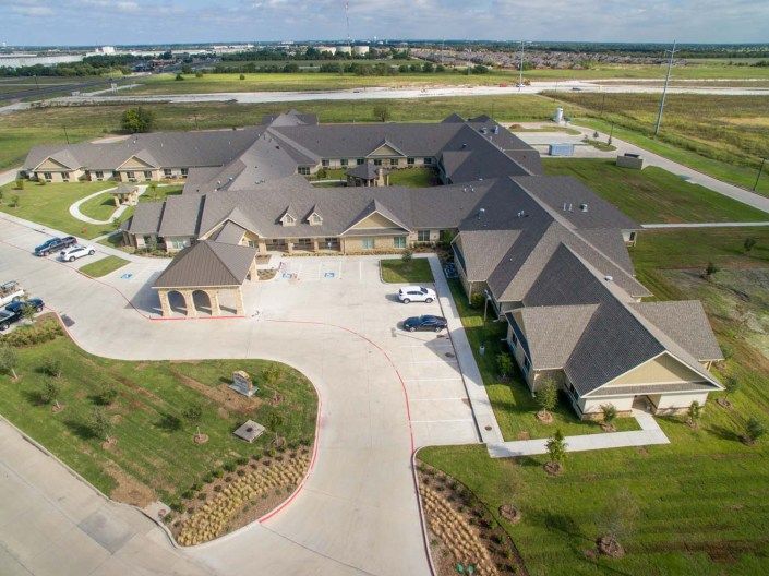 Aerial view of a large residential or commercial building with multiple wings and a circular driveway surrounded by greenery.