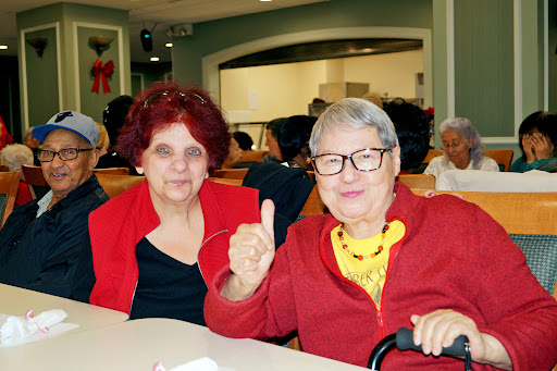 Two elderly women enjoying a moment together, dressed in red and sharing a smile.