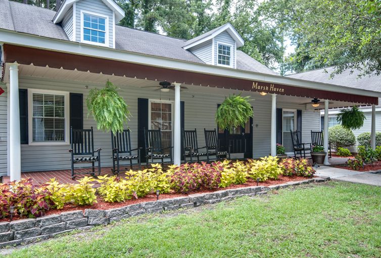 A charming house with a covered porch, featuring rocking chairs and well-maintained landscaping.