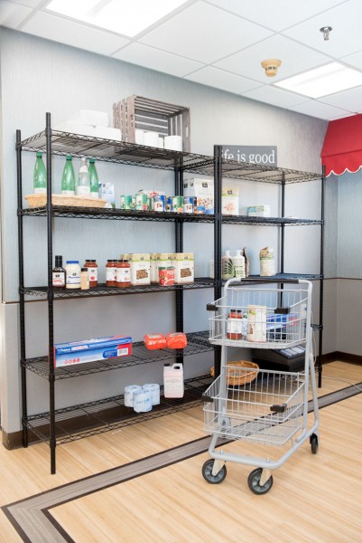 A store display with shelves holding various grocery items and an empty shopping cart nearby.