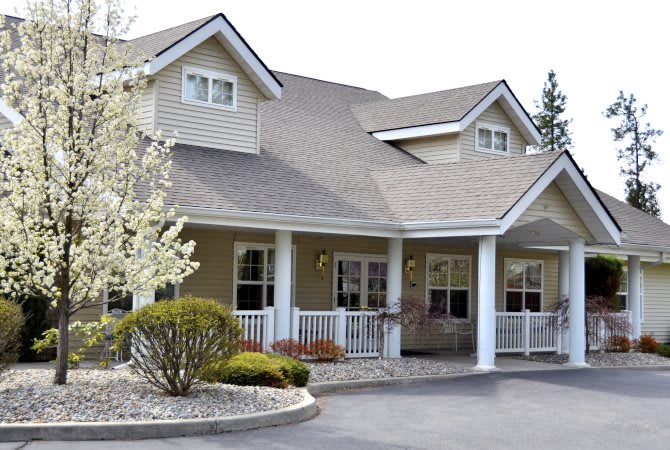 A suburban residential house with a porch and landscaped front yard.