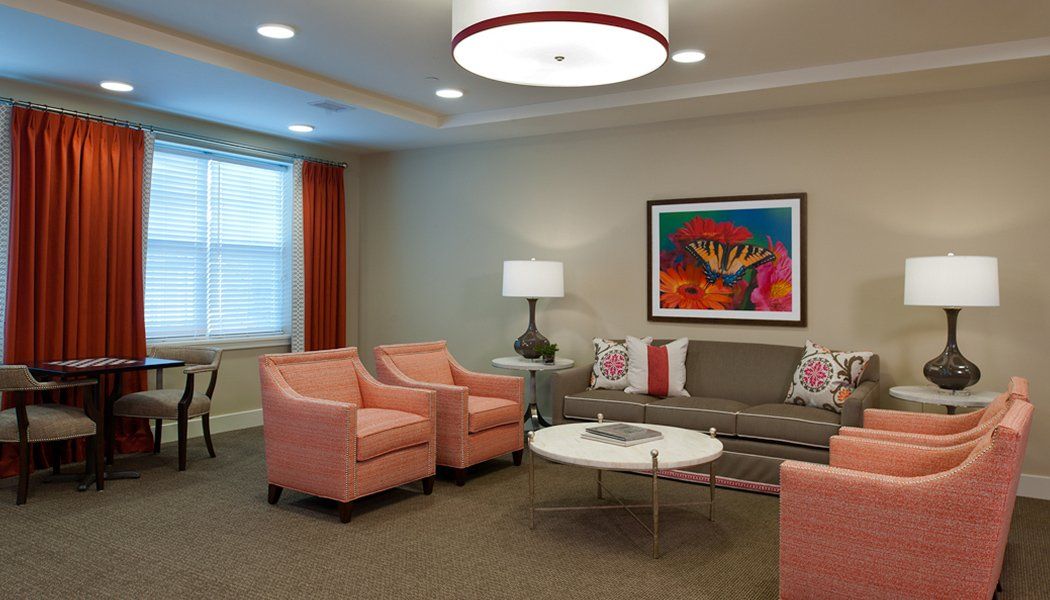 A modern living room with peach armchairs, a gray couch, and vibrant artwork on the wall.