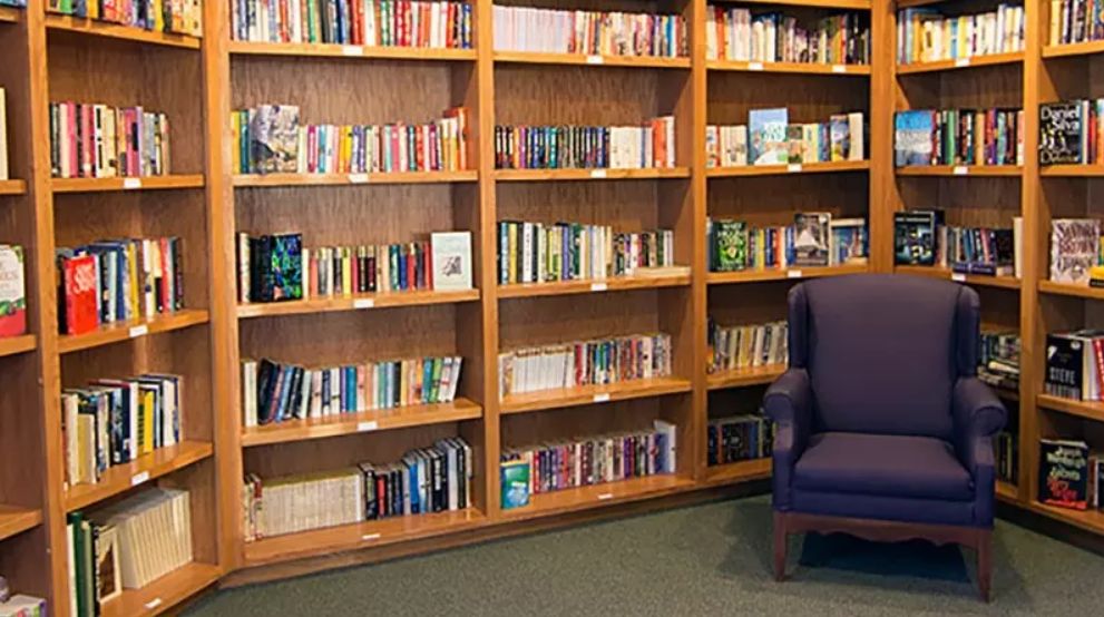 A cozy reading corner with a well-stocked bookshelf and an armchair.