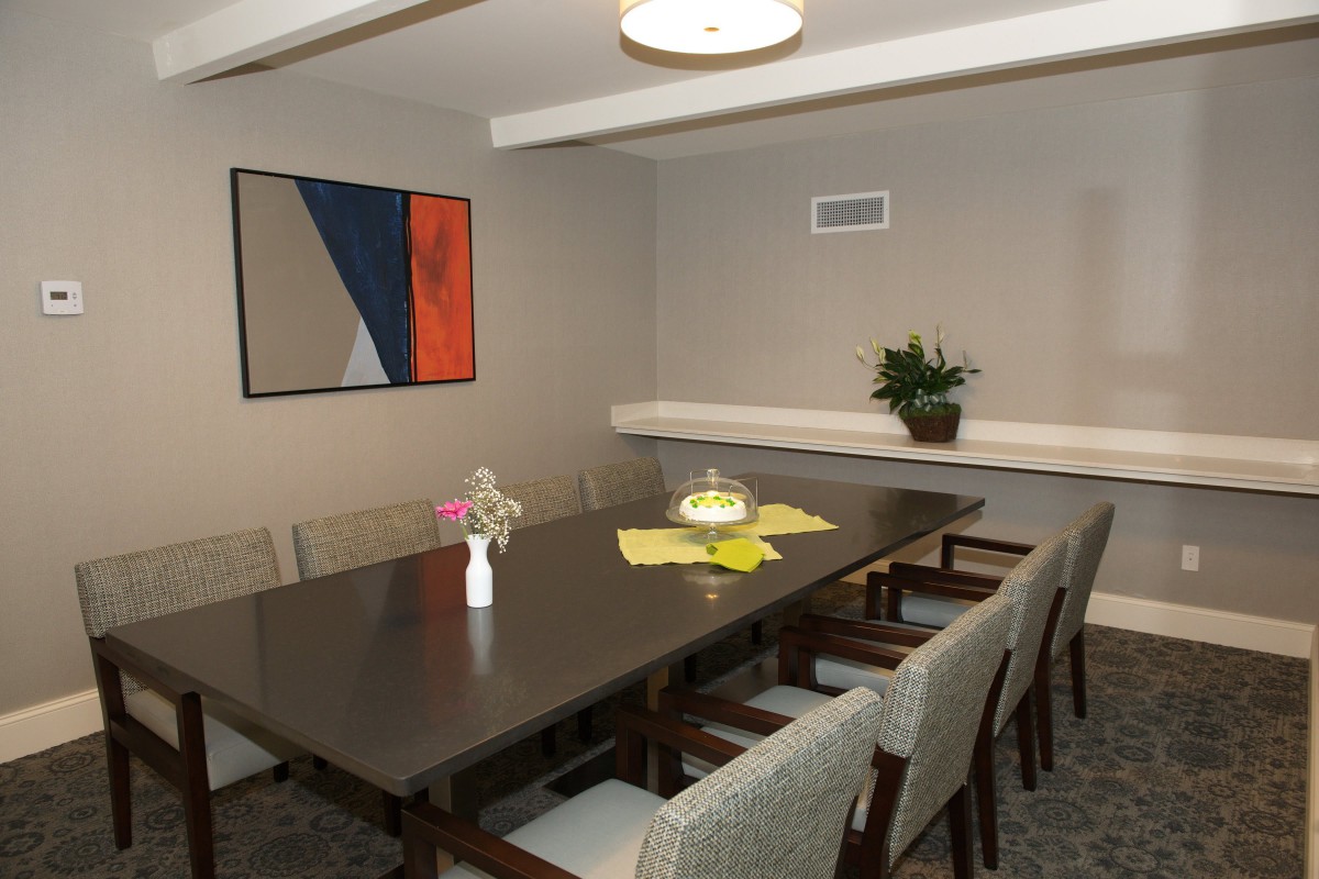 A modern dining room with a large table, surrounded by chairs and decorated with artwork and plants.