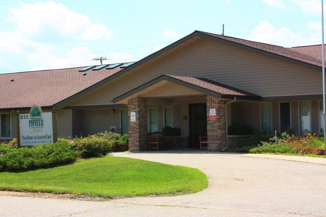 A single-story residential building with a well-kept lawn and a driveway leading to the entrance.