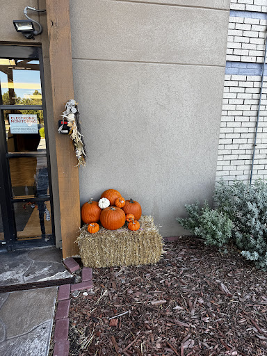 A cozy autumn display featuring a collection of pumpkins stacked on hay bales at the entrance.