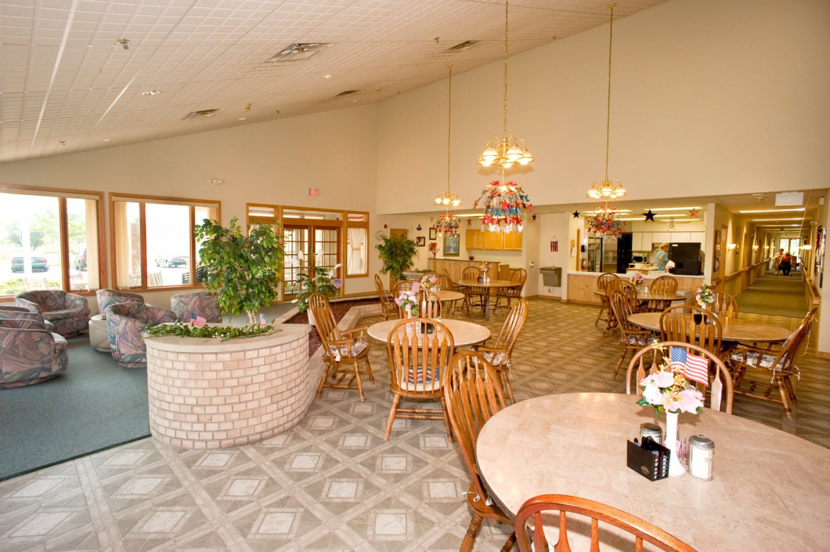 An inviting dining area with wooden tables and chairs, complemented by indoor plants and warm lighting.