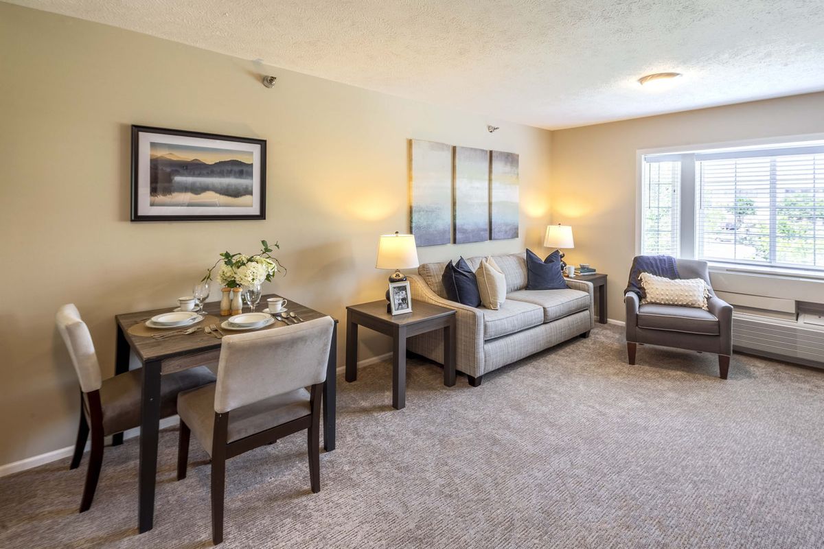 A cozy living room with a sofa, armchair, and dining table, featuring elegant decor and warm lighting.