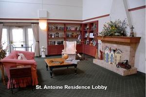 A cozy residential lobby with a bookshelf, armchair, and fireplace.