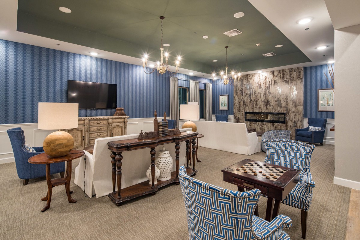 A stylish and modern living room with blue accents, featuring elegant chandeliers and comfortable seating.