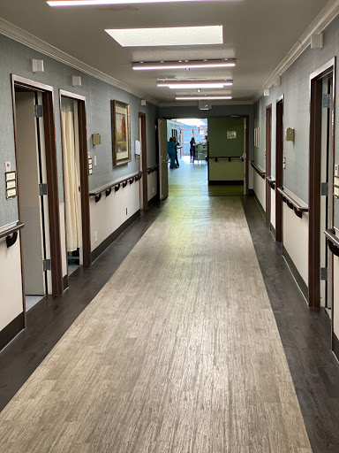A well-lit hallway in a healthcare facility, with doors leading to individual rooms.