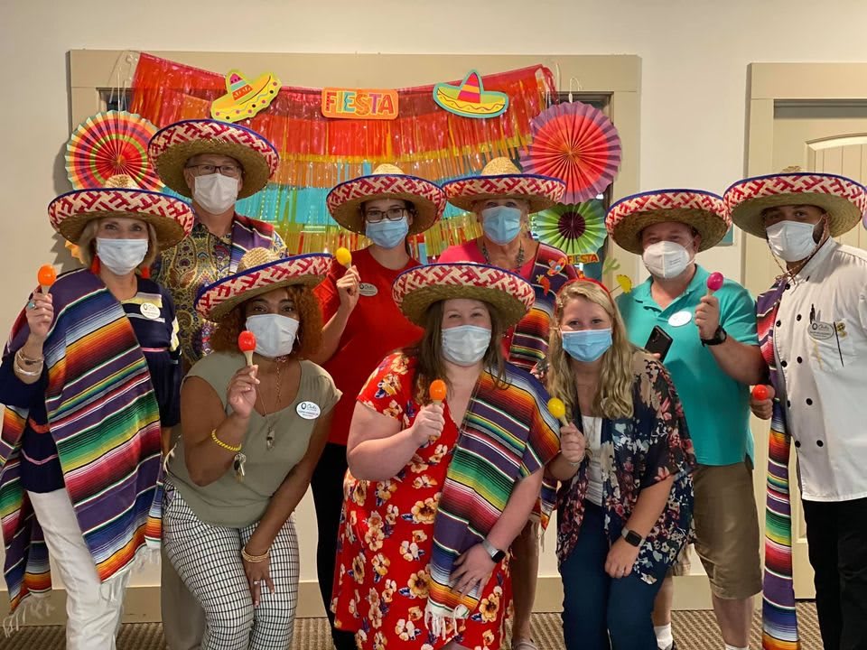 A group of people wearing sombreros and masks, posing for a festive celebration with colorful decorations.