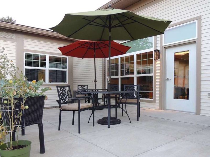 A cozy patio setup with a table, chairs, and two umbrellas providing shade.