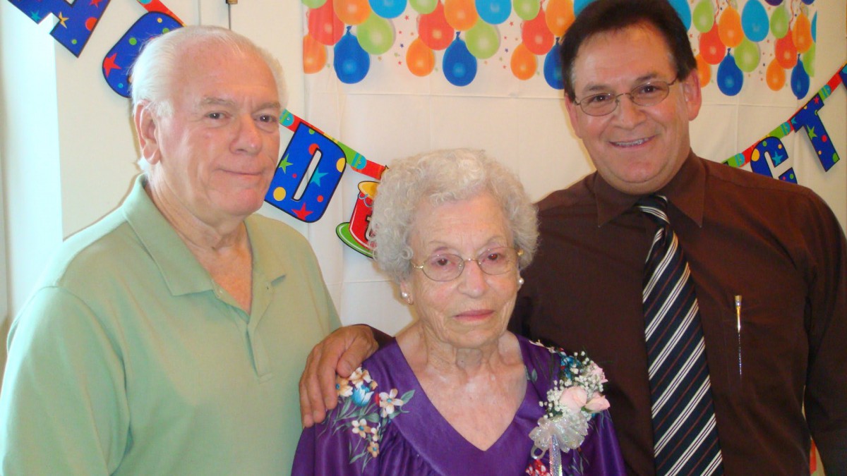 A family celebrating a special occasion with balloons and a festive banner.