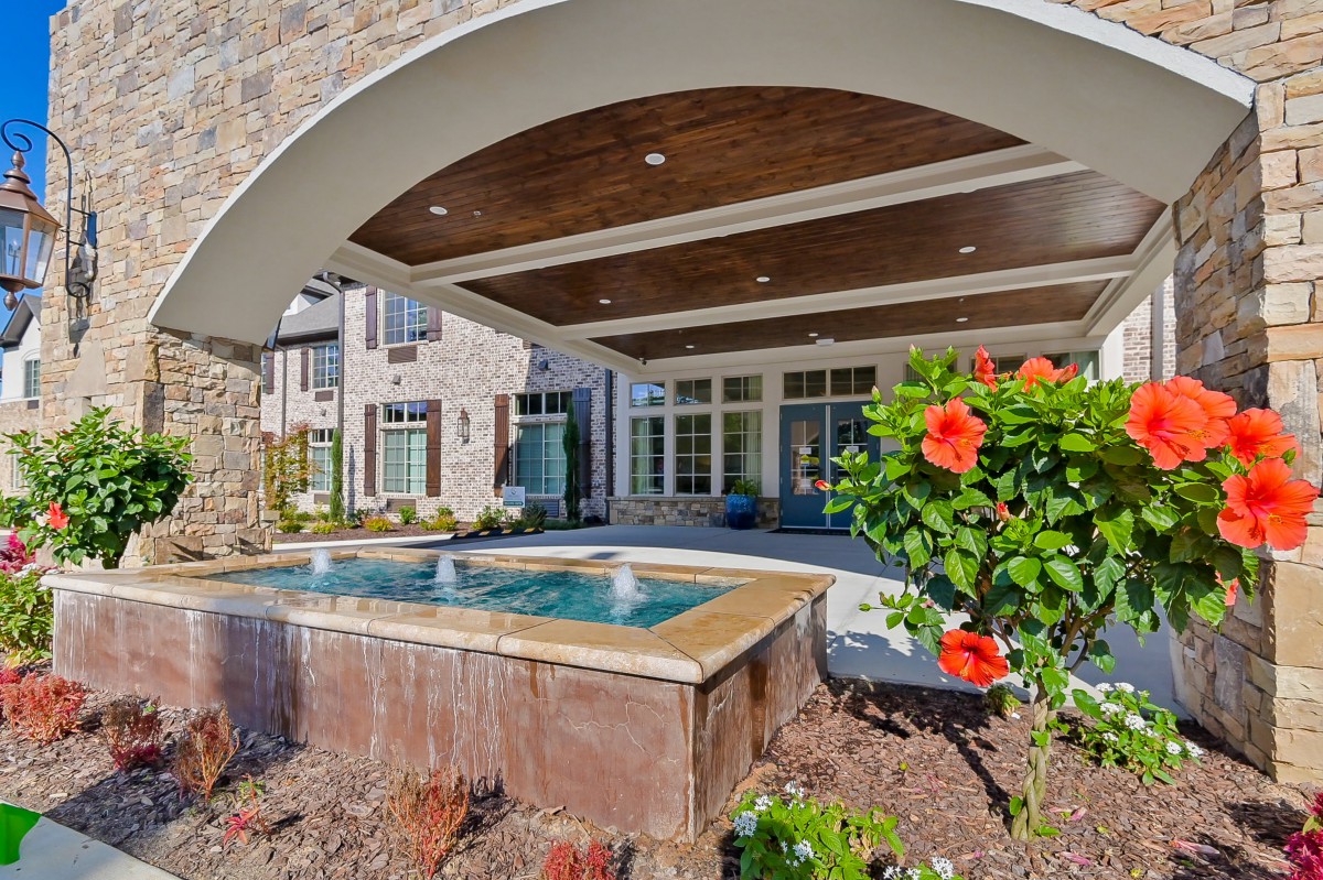 A luxurious outdoor patio with a hot tub and vibrant flowers, framed by an elegant archway.