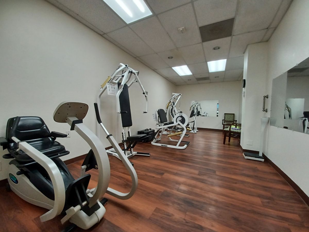 A clean and well-lit gym with modern exercise equipment on a wooden floor.