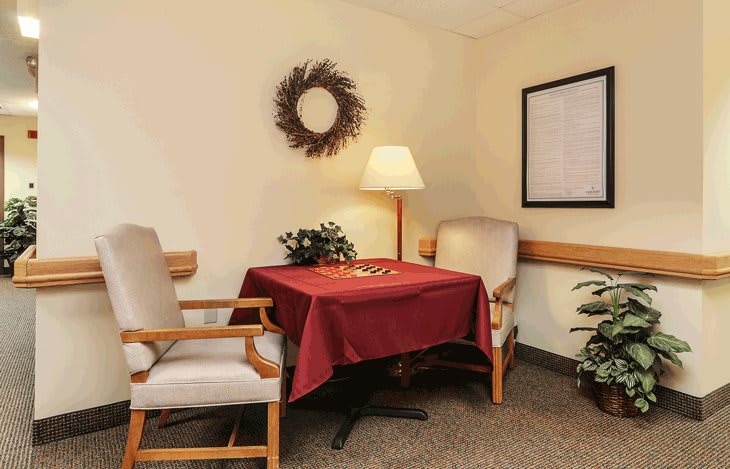 A cozy seating area with two chairs and a table, adorned with a wreath and a lamp.