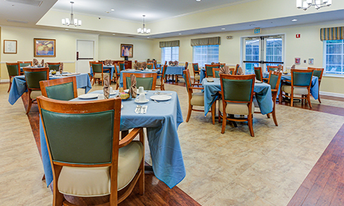 A well-arranged dining area with tables and chairs, set with blue tablecloths.