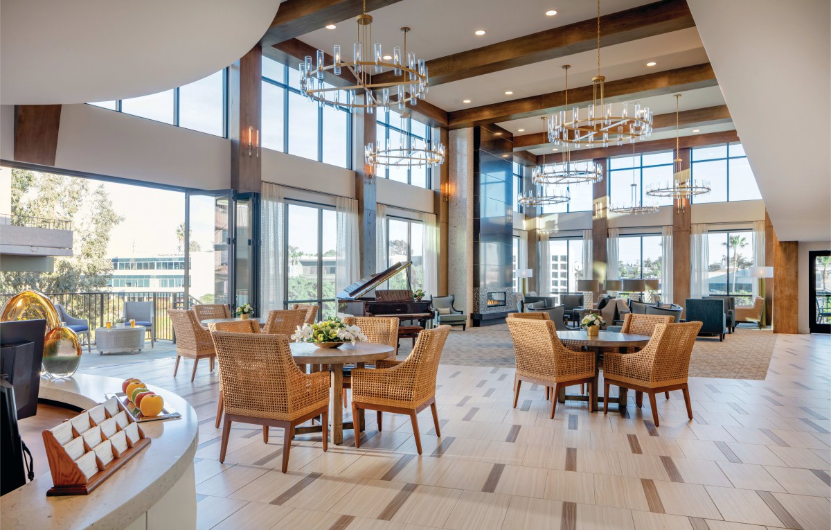 A modern dining area with large windows, natural light, and elegant chandeliers.