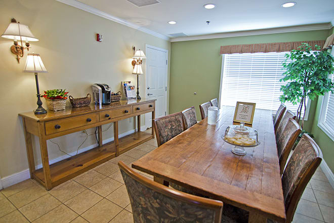 A cozy dining area with a wooden table and chairs, complemented by a coffee station in a well-lit room.