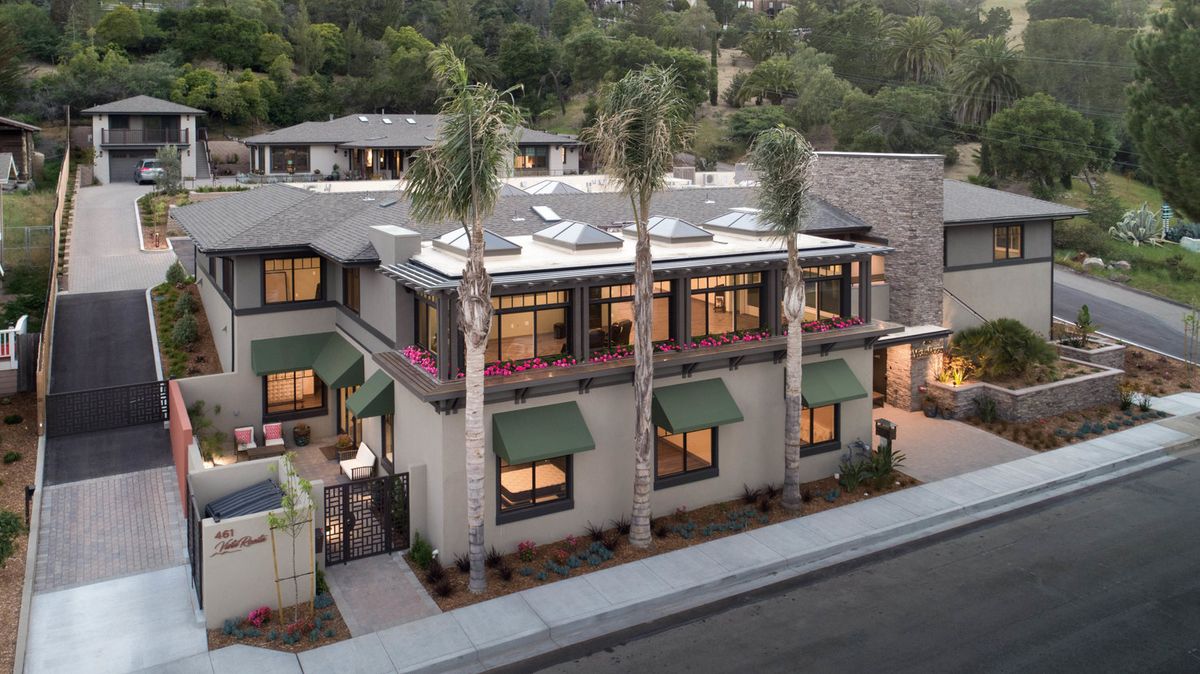 Modern residential building with palm trees lining the street.