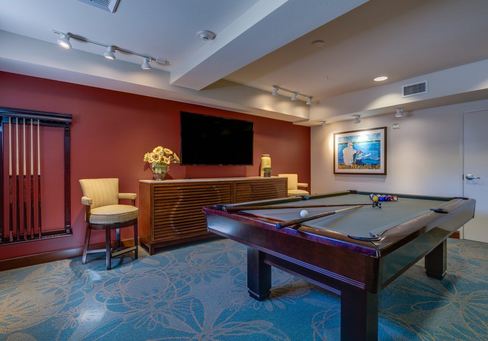 A stylish game room featuring a pool table, seating area, and a large television.