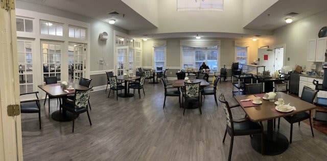 Empty dining area with tables and chairs set up near large windows.