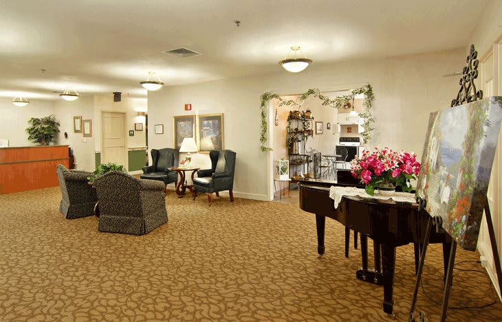 A cozy living room with a piano and seating area, featuring elegant decorations.